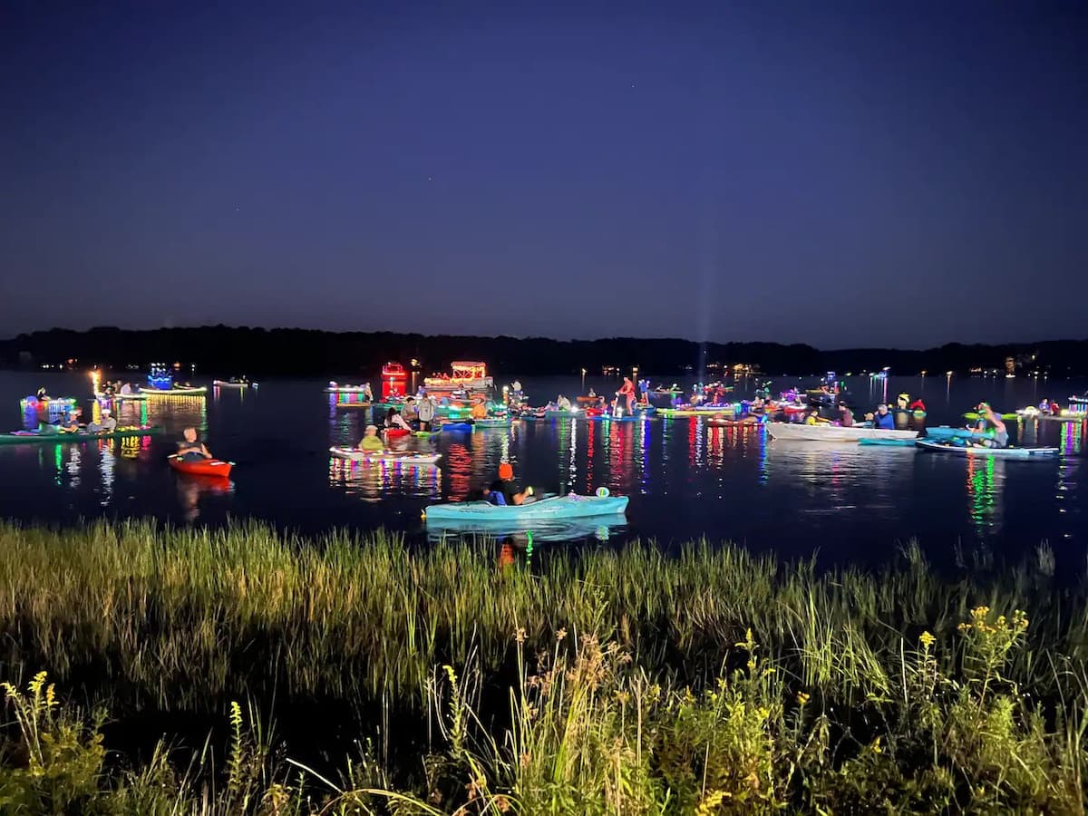 Colorfully lit kayaks and paddleboards on the lake at night