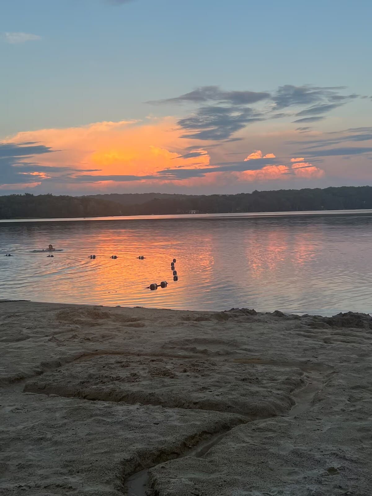 Sunset over the lake with a swimmer and a line of buoys